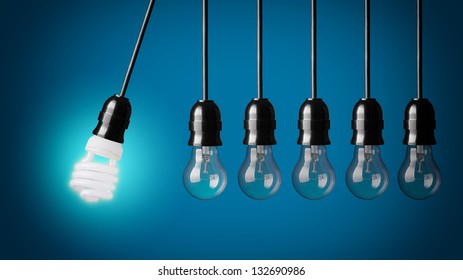 Perpetual Motion With Light Bulbs And Energy Saver Bulb. Idea Concept On Blue Background.