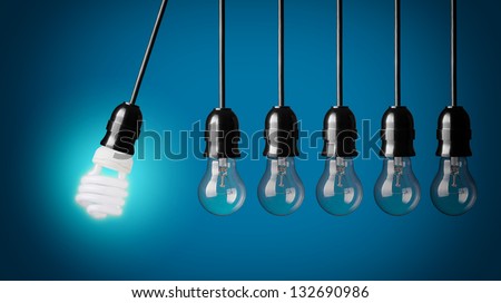 Perpetual motion with light bulbs and energy saver bulb. Idea concept on blue background.