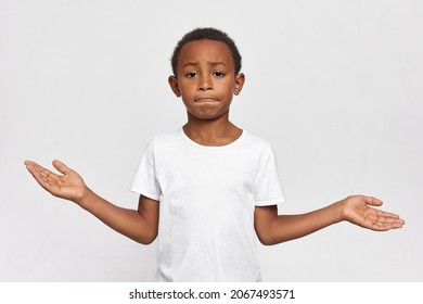 Perplexed 9-year-old Kid Tighten Lips, Shrugging, Throwing Hands Up, Feeling Confused, Full Of Questions, Having Dilemma. Cute Children. Human Emotions And Face Expressions. Body Language