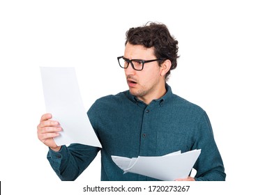 Perplexed Businessman Looking Stunned At Paper Documents Isolated On White Background. Confused Business Person In Trouble As Holds Different Sheets With Negative Financial Reports. Frightened Guy.