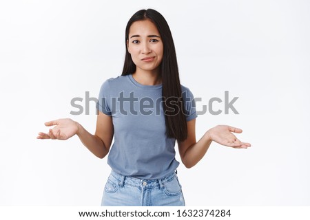 Perplexed and indecisive, skeptical cute asian girl cant decide, shrugging with hands spread sideways, smirk and look camera doubtful, not sure, puzzled to give answer, standing white background
