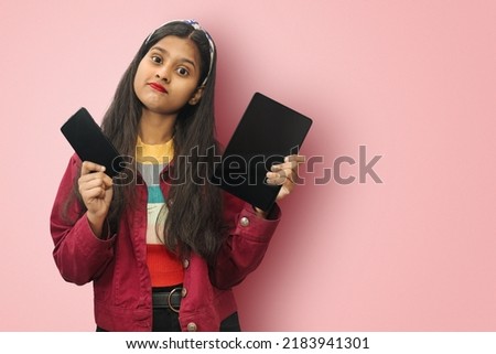 Perplexed and indecisive, skeptical cute indian asian girl posing isolated can't decide, not sure with tablet and phone puzzled to give answer with empty space for text