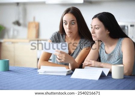 Perplexed interracial roommates checking strange bill in the kitchen at home