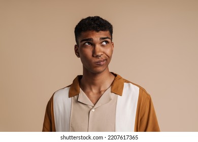 Perplexed Man Grimacing While Looking Aside Isolated Over Beige Background