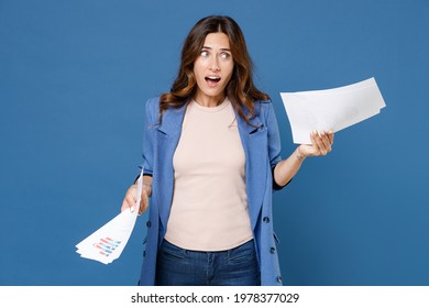 Perplexed puzzled worried shocked young brunette woman 20s wearing basic jacket hold papers document keeping mouth open looking aside isolated on bright blue colour wall background studio portrait - Shutterstock ID 1978377029