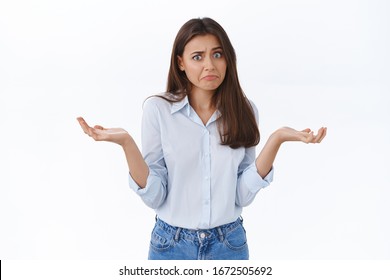Perplexed silly young worried woman dont know what to say, have no answer, look embarrassed say sorry and shrugging with hands spread sideways, being clueless and indecisive what do, white background