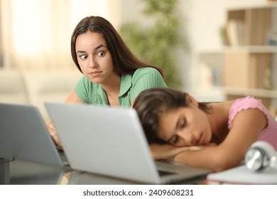 Perplexed student looking at her classmate sleeping at home