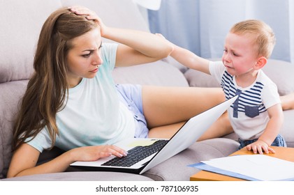 Perplexed Woman Is Having Problems With Work While Child Crying At Home.