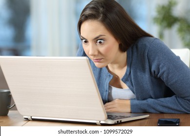 Perplexed Woman Reading Online News In A Laptop On A Desk At Home