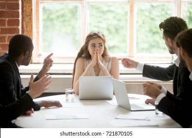 Perplexed young woman looking at coworkers pointing fingers at her. Disgruntled multiethnic team scolding female colleague who made bad work-related mistake. Stressed upset business lady in trouble.  - Powered by Shutterstock