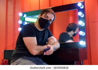 Persian man with mask sitting and leaning against mirror in the makeup room - Shutterstock ID 1819050818