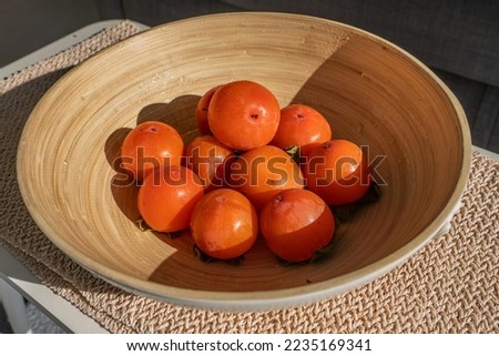 Persimmons in a bowl. Fresh fruits. Healthy food. Orange-colored fruits. Vitamins. Exotic dessert. Juicy persimmons. Close-up. Daylighting.