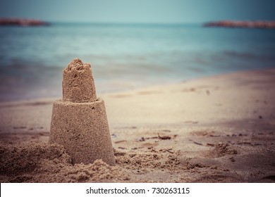 Persistent tower of the sand castle washes away in the sea water.