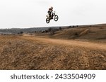 A person is airborne on a motocross dirt bike jumping with a helmet in the sky