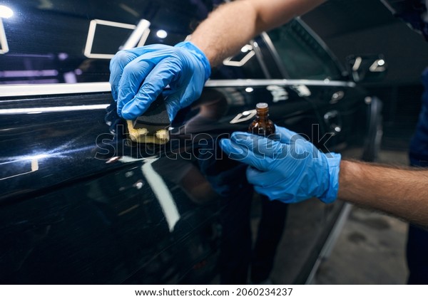 Person applying\
coating on car surface\
scratches