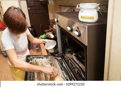 Person Applying Mixed Baking Soda Onto Surface Of Oven For Effective And Safe Cleaning