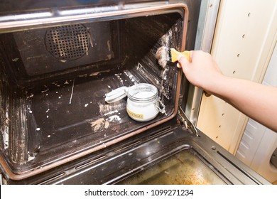 Person Applying Mixed Baking Soda Onto Surface Of Oven For Effective And Safe Cleaning