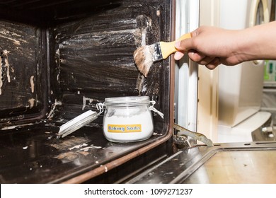 Person Applying Mixed Baking Soda Onto Surface Of Oven For Effective And Safe Cleaning