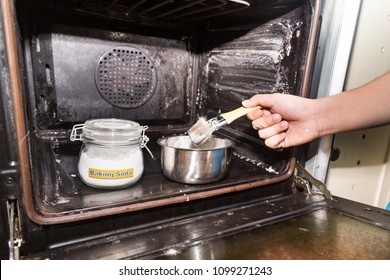 Person Applying Mixed Baking Soda Onto Surface Of Oven For Effective And Safe Cleaning