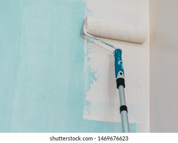 Person Appplying Paint On Wall Using Roller Brush. Home Renovation Concept.