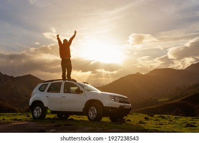 person with arms raised and on the roof of his off-road car watching the sunset on the mountain after a day of travel and adventure. Active turism. mountain activities. - Powered by Shutterstock