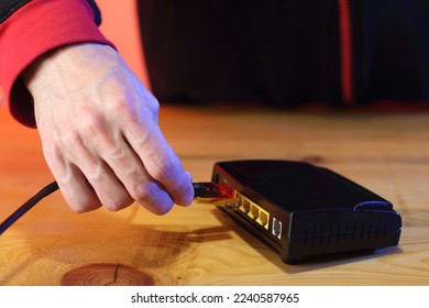 person in background inserting internet cable into old adsl modem