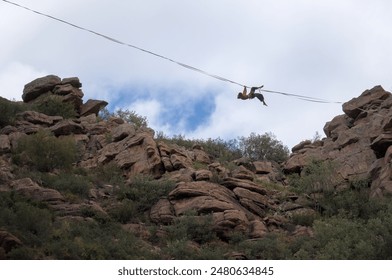 A person is balancing on a tightrope stretched between rocky cliffs. - Powered by Shutterstock