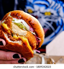 Person With Black Painted Finger Nails Holding A Fresh Vegan Plant Based Burger In A Bun