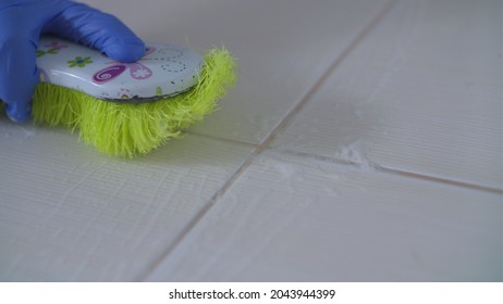 Person In Blue Latex Glove Cleaning Drity Floor Tiles And Grout Using Brush