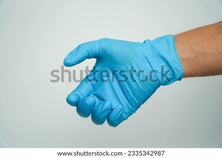 Person in blue latex gloves holding something against on a gray background,Hand in blue glove.