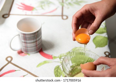 Person Breaking An Egg Shell To Separate The Yolk From The White.