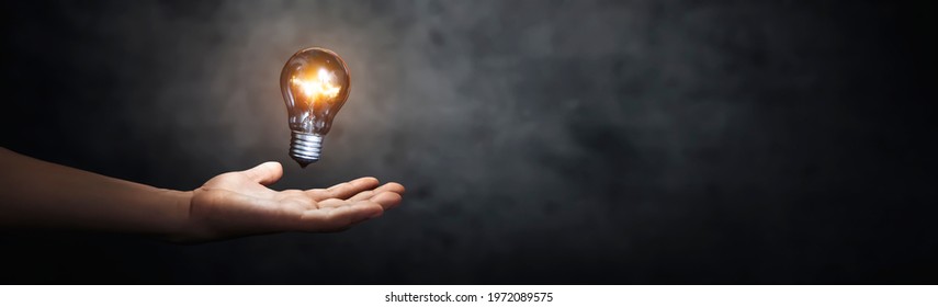 person with a bright light bulb floating above his hand - copy space
