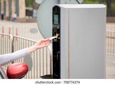 Person in the car inserting into or removing ticket from parking vending machine. Paying, entering parking lot or exiting garage concept. Daytime setting.