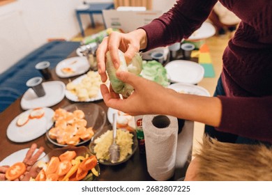 A person is carefully preparing a delicious array of food at a table that is filled with an inviting selection of various snacks and fresh fruits