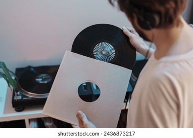 A person in a casual setting enjoys listening to a vinyl record on a turntable. - Powered by Shutterstock