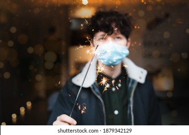 A Person is celebrating with sparkler siklvester in lockdown at home. Wearing a mask for prevention, concept social distancing and lockdown during covid-19 or corona virus.