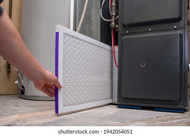 A person changing an clean air filter on a high efficiency furnace