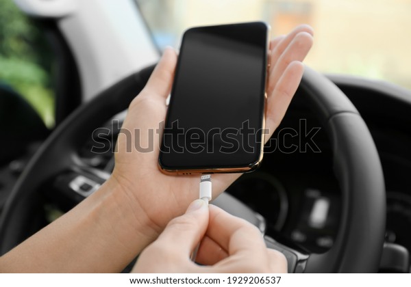 Person charging\
phone with USB cable in\
car