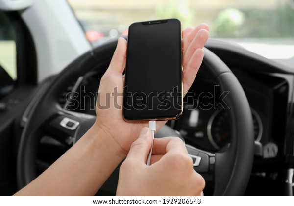 Person charging\
phone with USB cable in\
car
