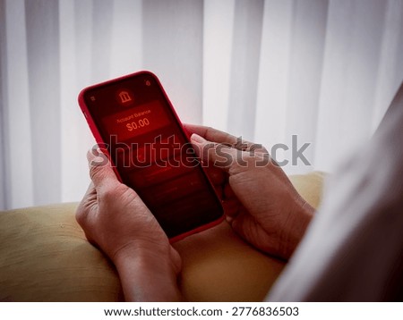 Person checking low balance, empty bank account on mobile banking app with red alert screen. Financial crisis, money shortage, personal finance problem, economic stress and digital payment risk.