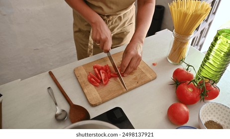 Person chopping tomatoes for an Italian meal preparation with fresh ingredients - Powered by Shutterstock