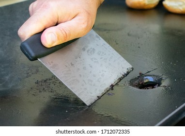 A Person Cleaning A Griddle