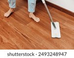 Person cleaning hardwood floor with wooden mop