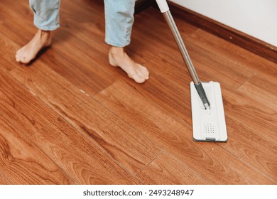 Person cleaning hardwood floor with wooden mop - Powered by Shutterstock