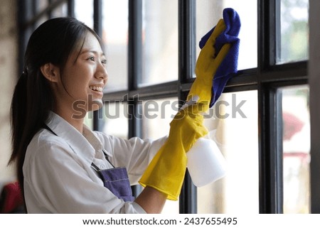 Person cleaning the room, cleaning staff is using cloth and spraying disinfectant to wipe the glass in the company office room. Cleaning staff. Maintaining cleanliness.