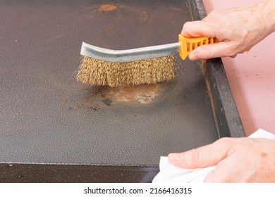 Person Cleaning Rust From A Sheet Metal, With A Wire Brush