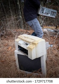 Person collecting old computer parts during an e-waste recycling event in the woods