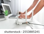 Person connecting modern wi-fi router on light table in living room