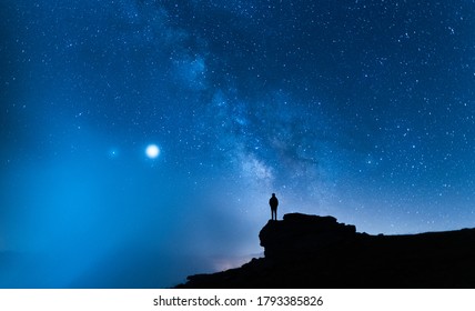 Person Contemplating The Vastness Of The Universe. Small Silhouette Of A Man Under The Milky Way And The Magical Starry Sky. Concept Of Human Smallness.