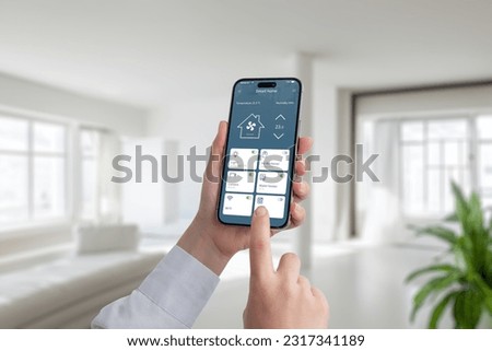 Person controls the temperature and lighting in the house with the help of an app on a mobile phone. A modern smart home application with the most important smart controls